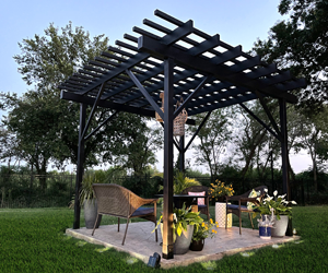 Modern steel pergola creating an outdoor living space with chairs and plants.