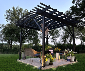 Pergola d'acier moderne créant un espace de vie extérieur avec des chaises et des plantes.