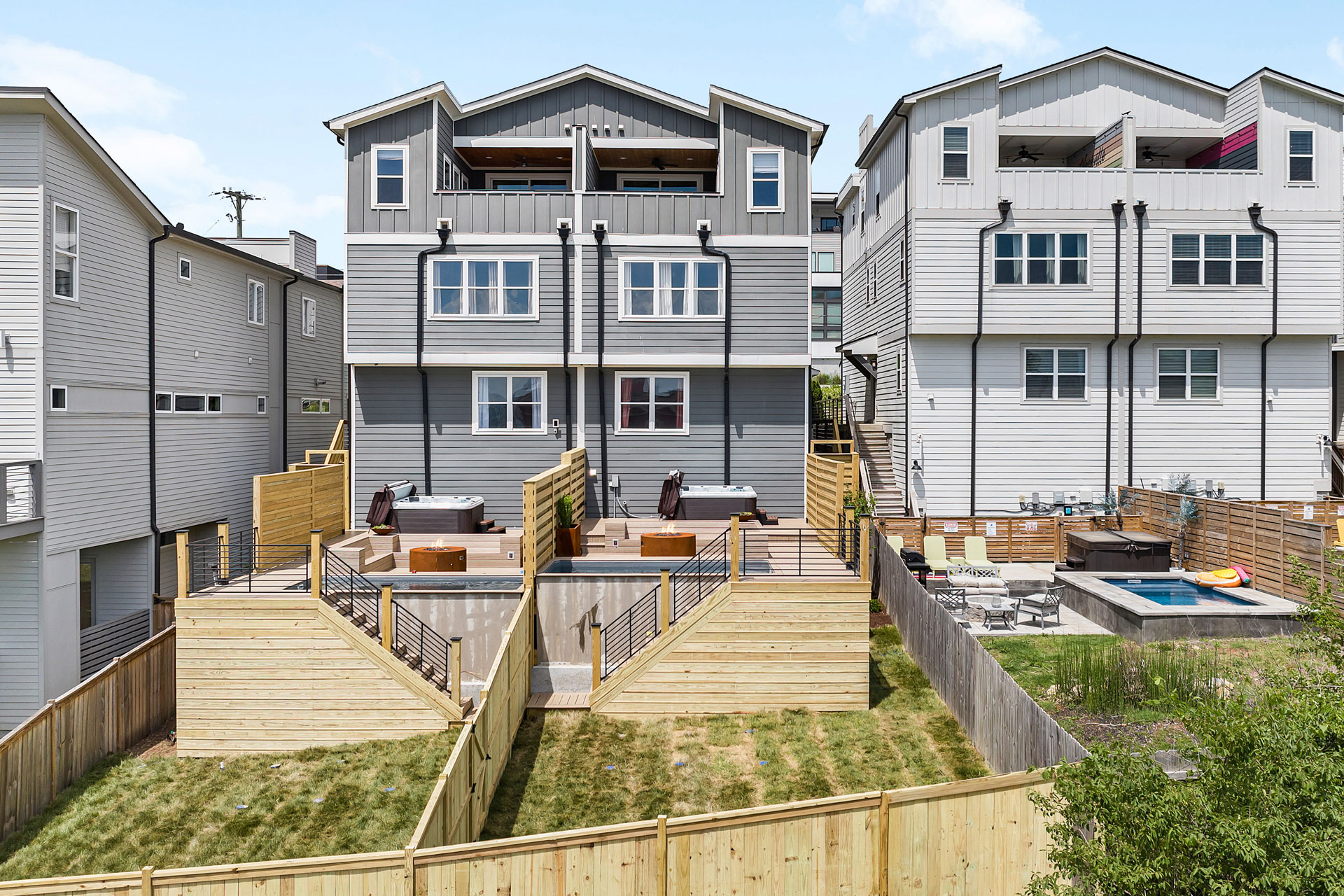 Multi-level backyard deck with metal stair railings, featuring distinct outdoor zones for entertainment and relaxation.