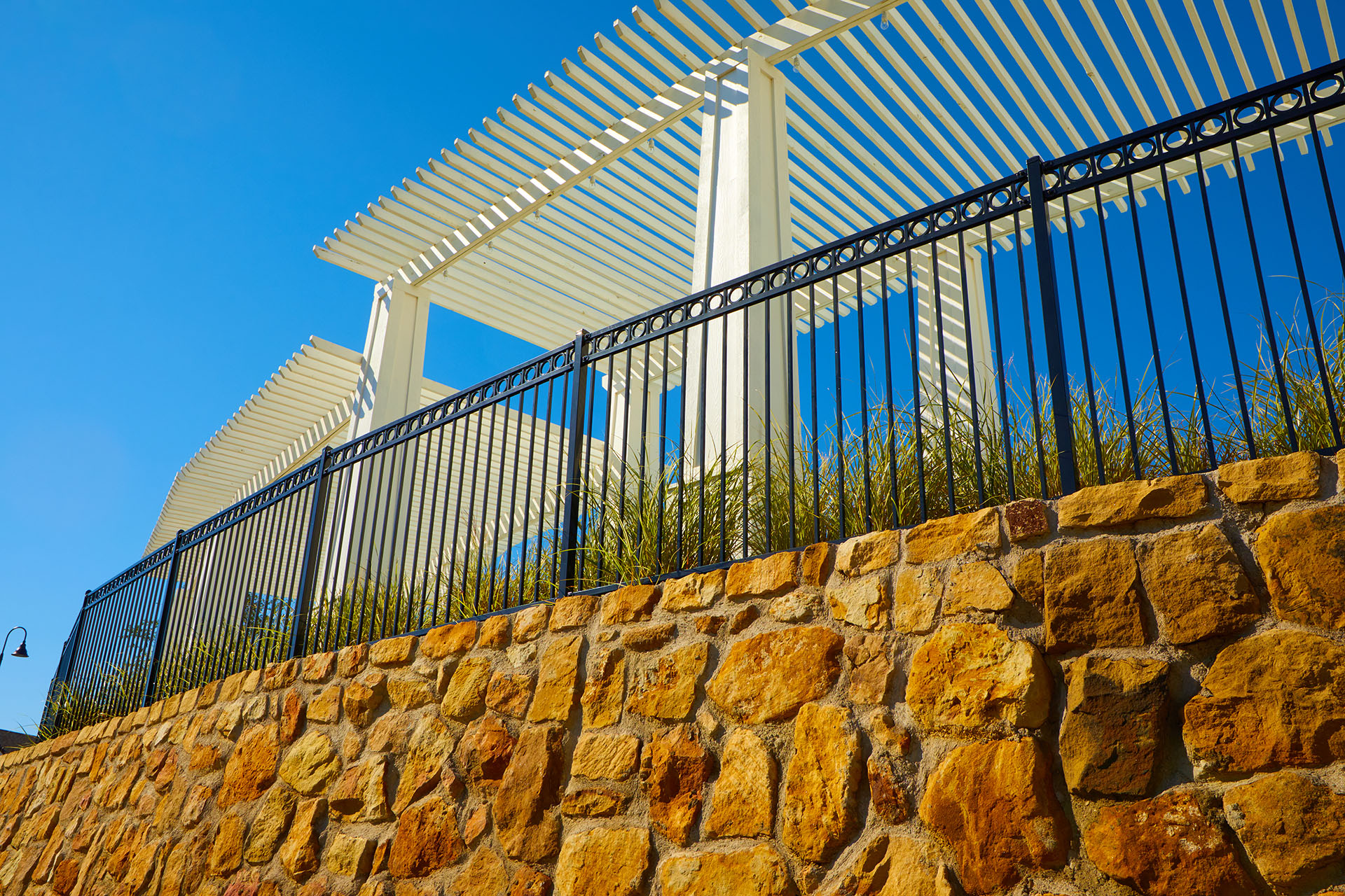 A decorative stone wall featuring a steel fence, illustrating a stylish residential fencing option.