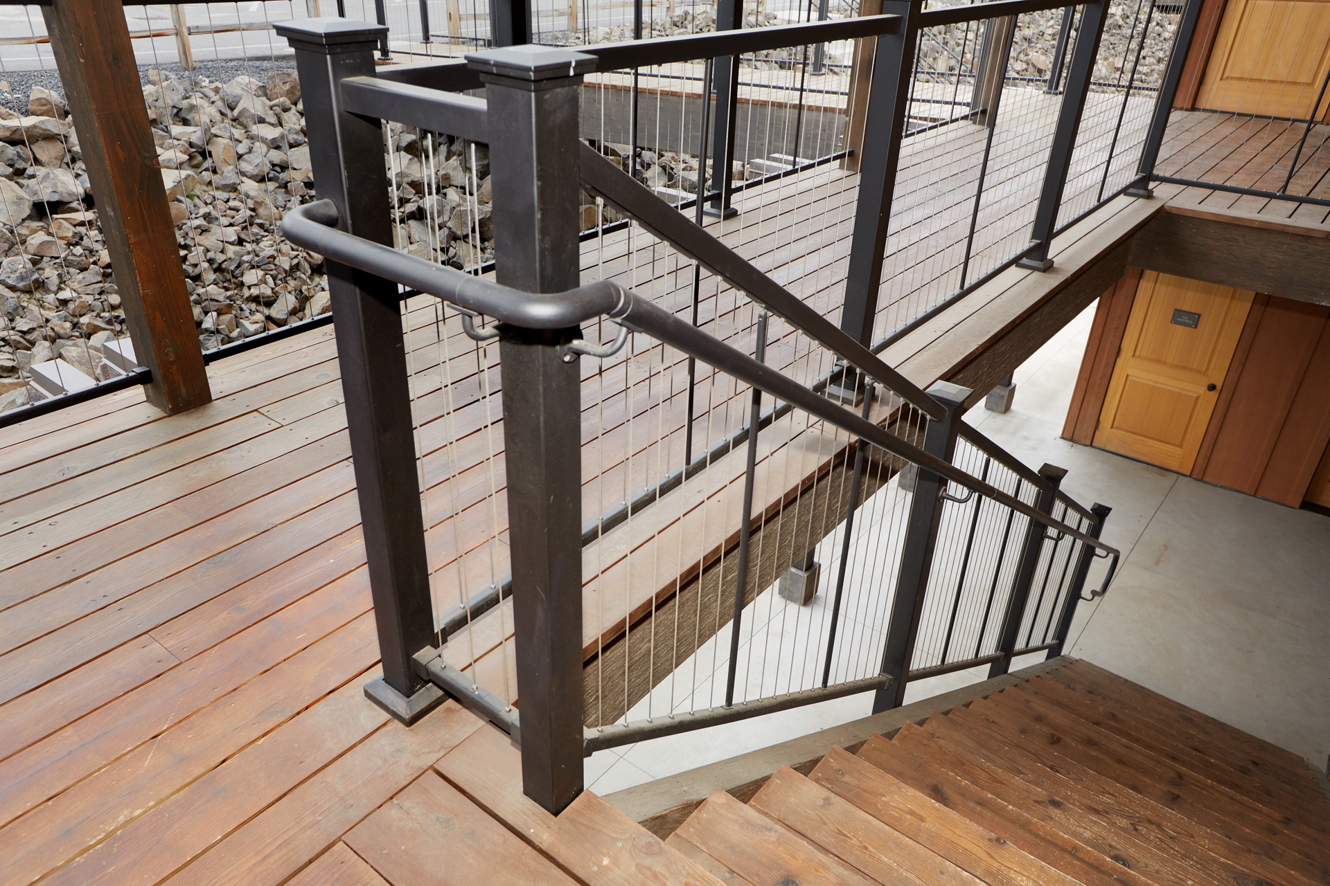 Brown Deck stairs with steel cable railing leading to a multi-level entertainment area.