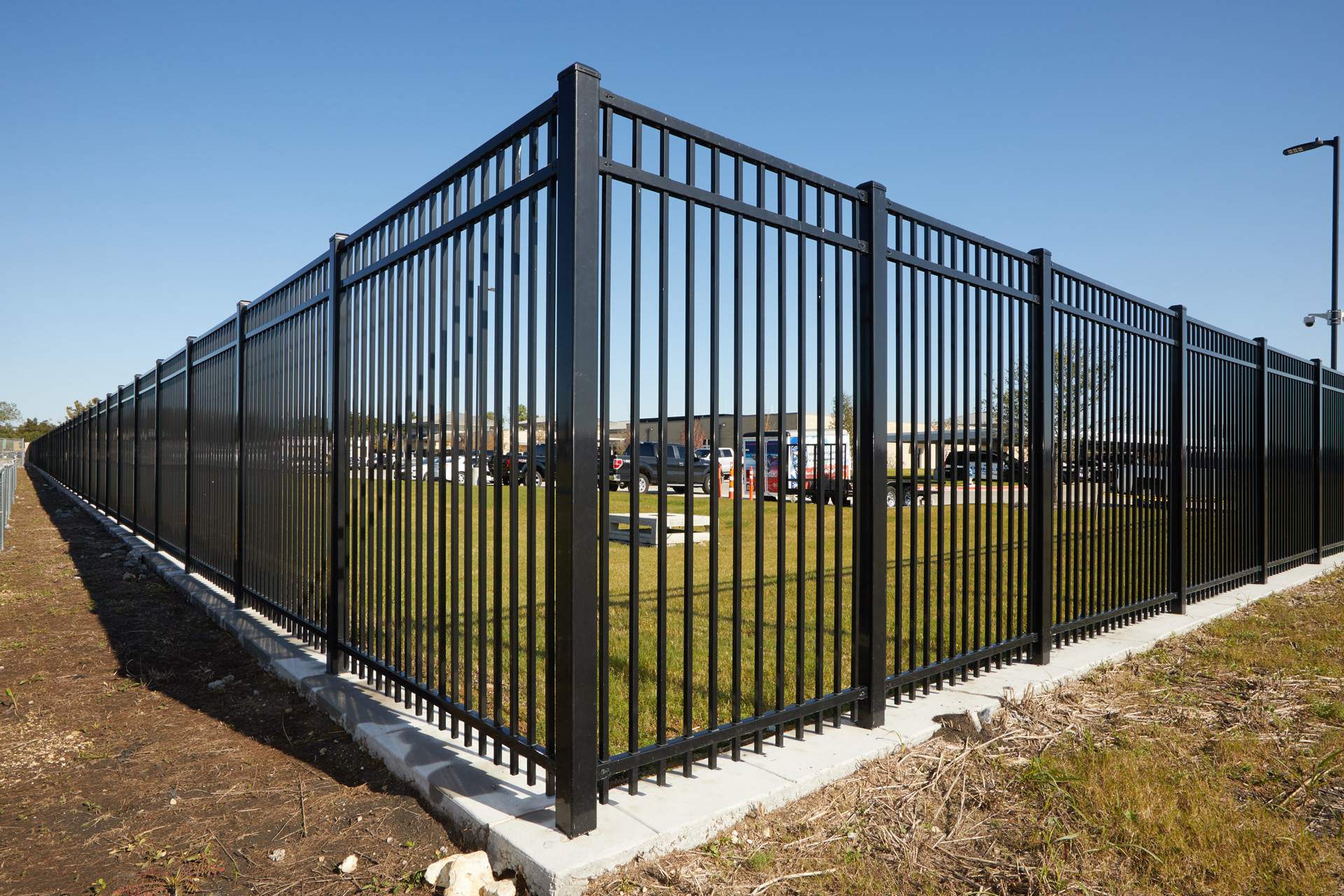 Tall metal fencing creates a secure perimeter around the parking lot. 