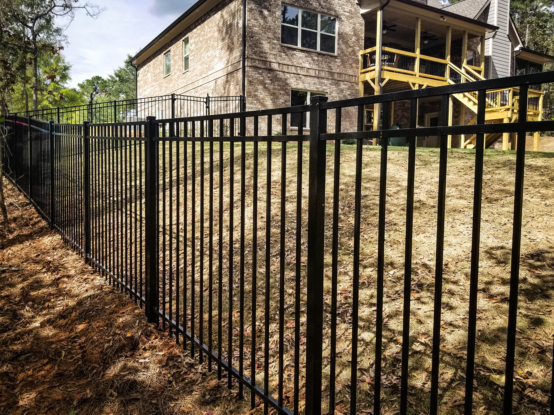Aluminum fence installed along a sloped backyard with multi-level deck.