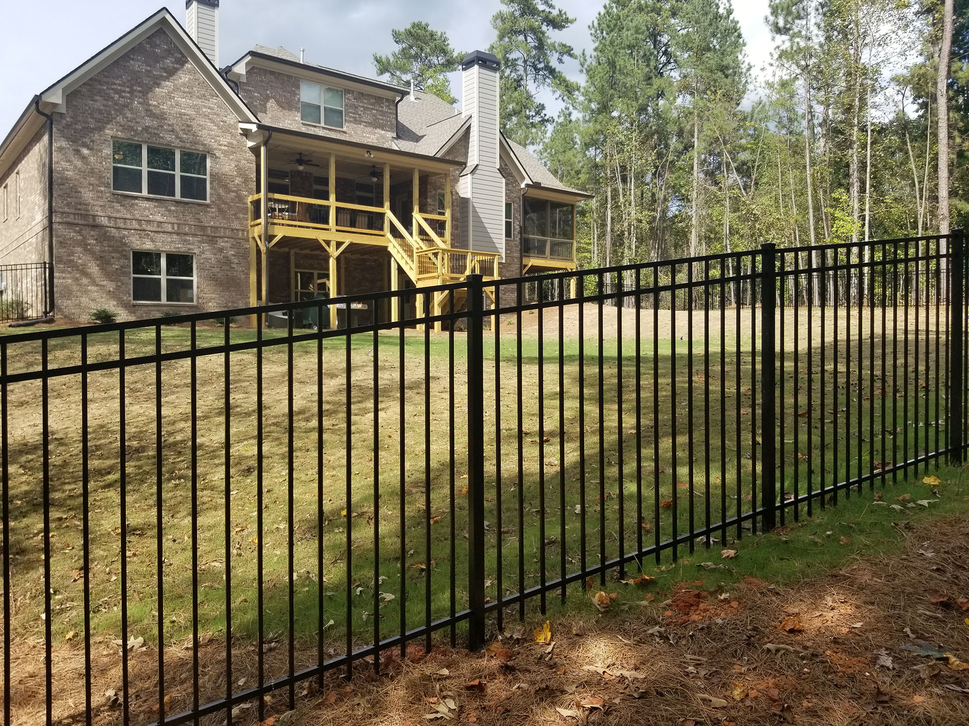 A sturdy fence encloses a residential property, enhancing privacy and complementing the house's exterior.