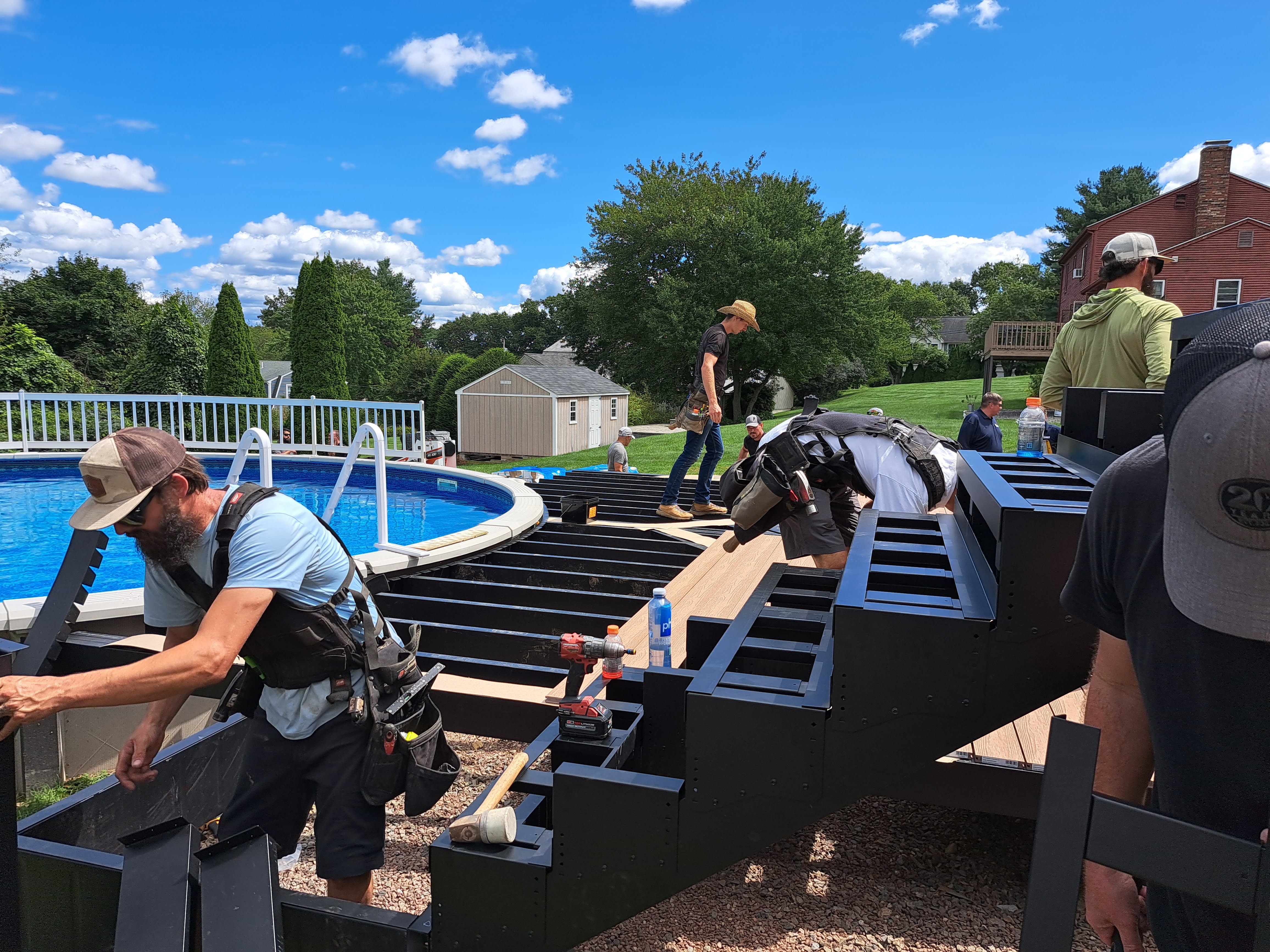 Ravin Builders installing steel deck framing around a pool, focusing on measurements and alignment.