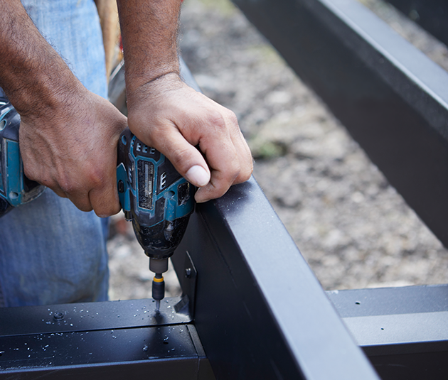 Un hombre perforando una estructura de acero para deck negra.