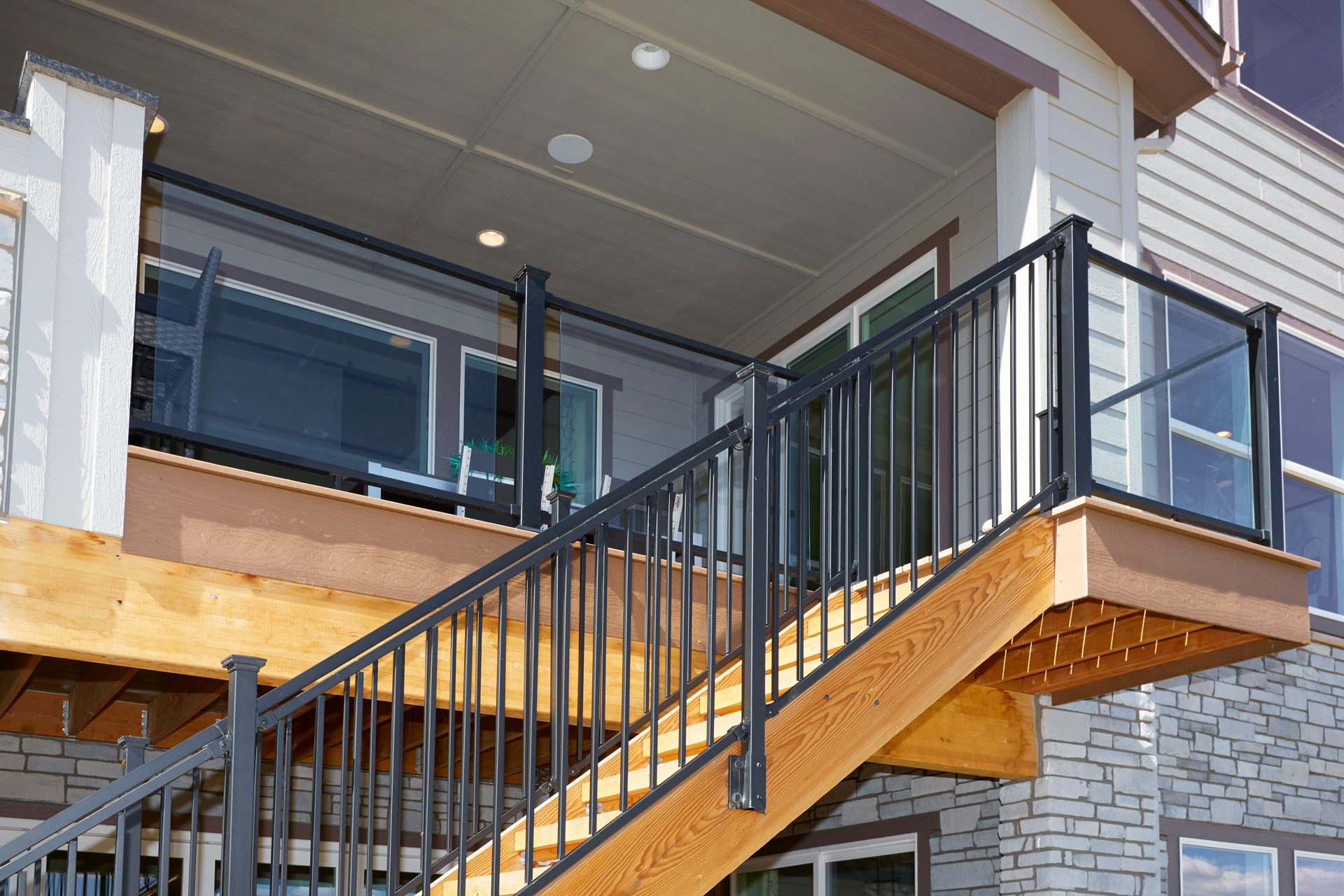 Close up view of glass railing with deck stairs off the back of the house. 