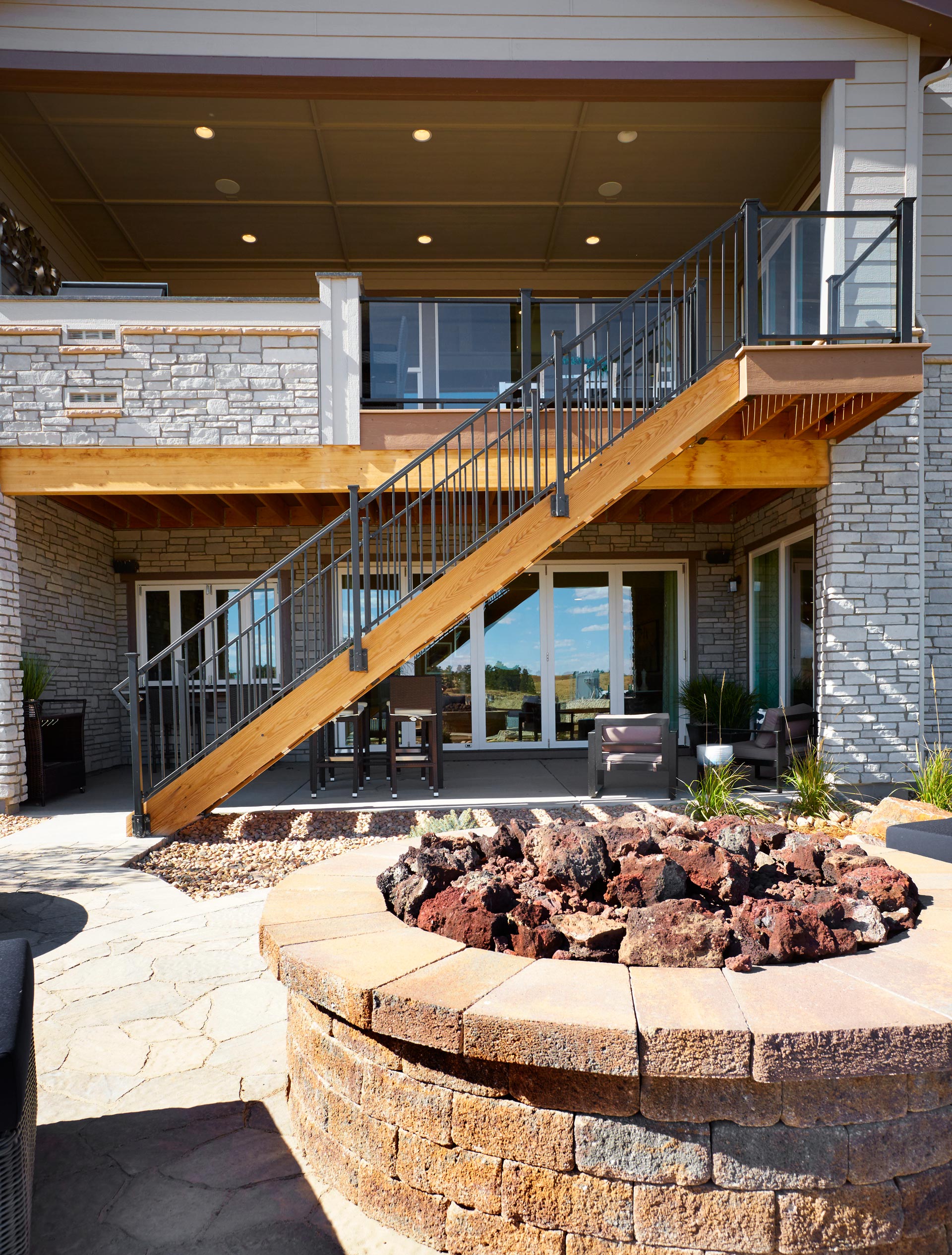 Large stone fireplace with deck stairs from upper deck in background.