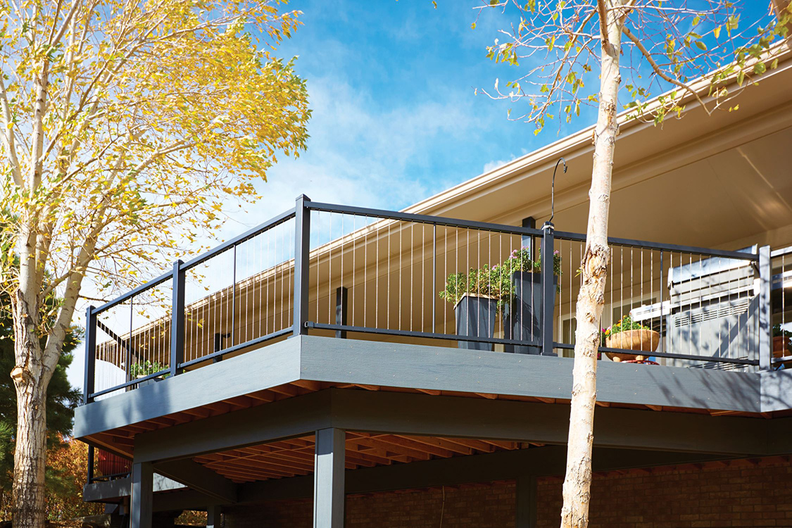 Upper deck with cable railing and blue sky and trees surrounding the deck. 