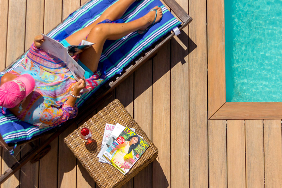 Woman reading poolside on a composite deck.