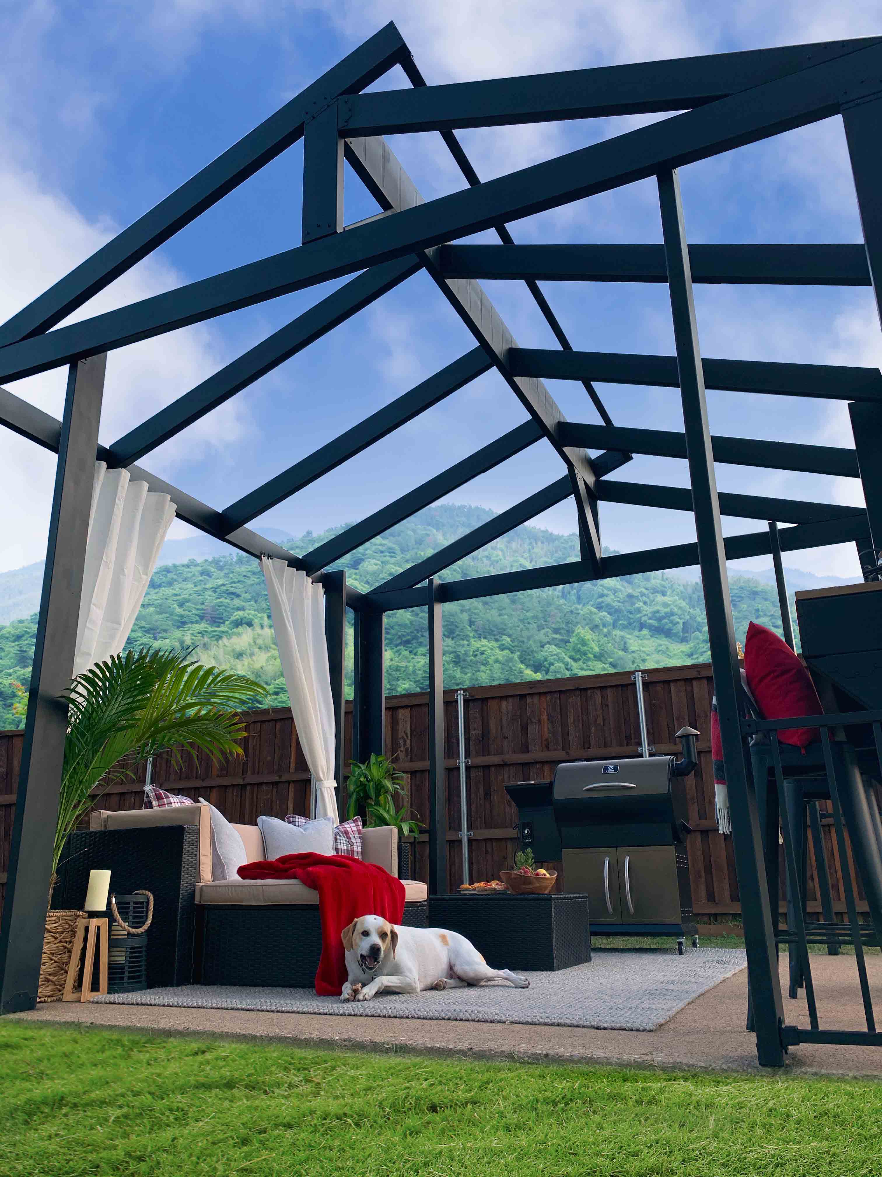 Steel Pergola over outdoor living space with a dog enjoying the shade by the couch. 