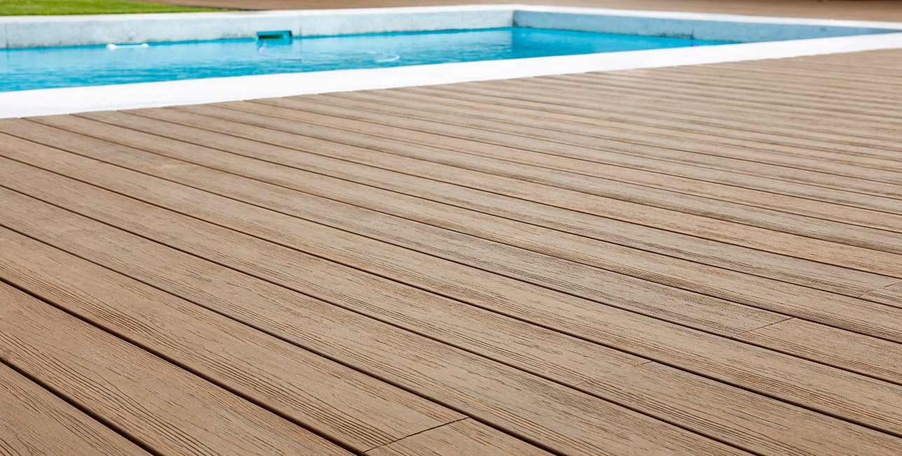 Close up image of capped bamboo-PVC composite decking with pool in background.