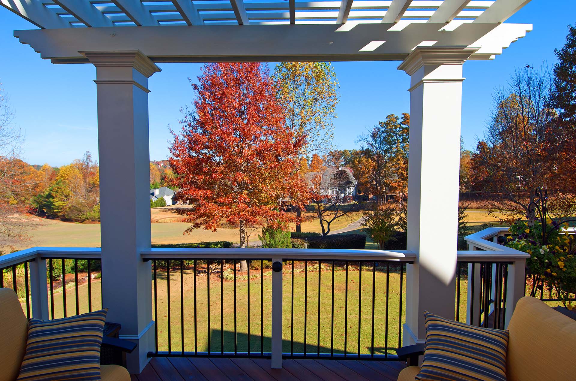 Deck with metal railing overlooking a backyard in autumn.