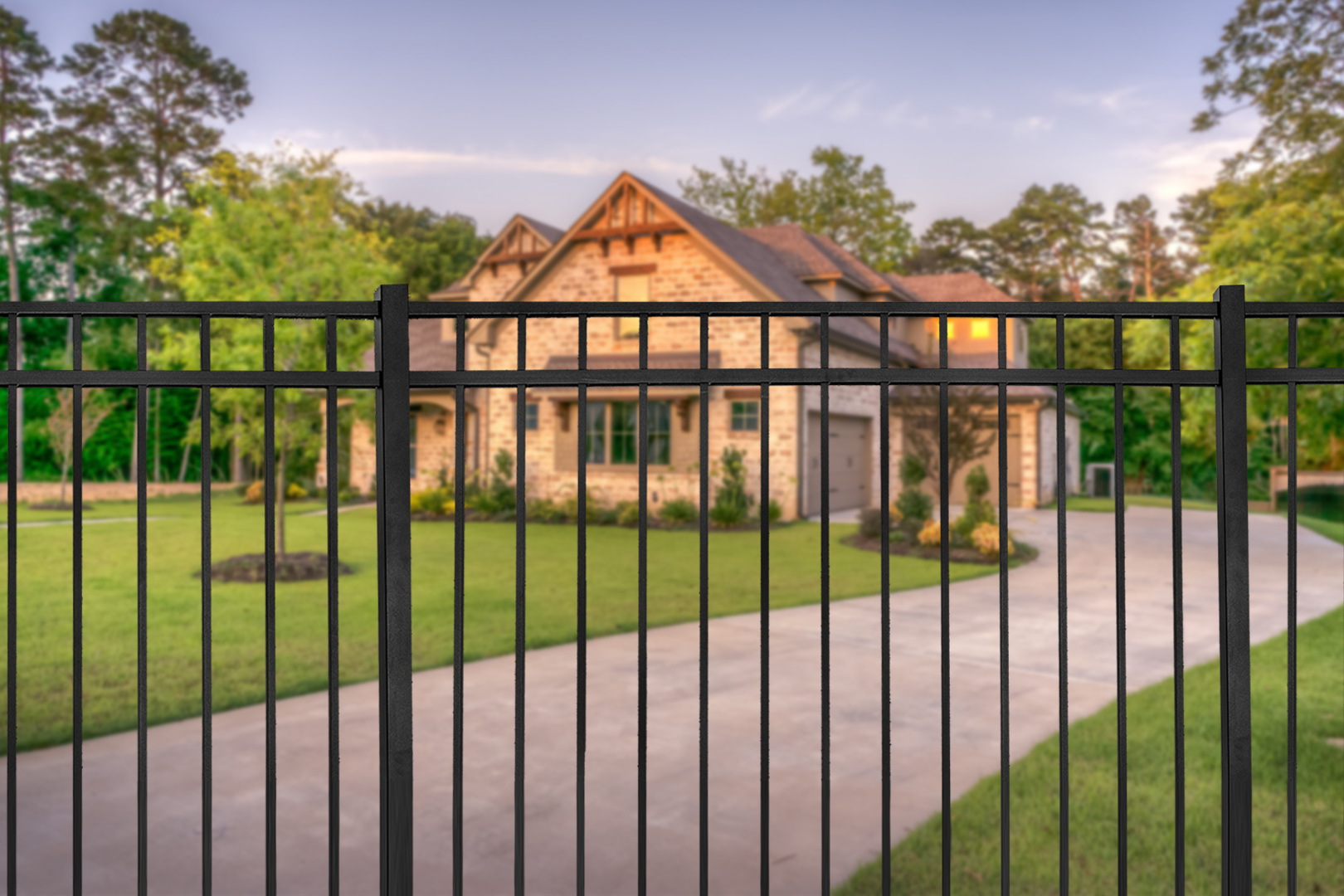Steel fencing in front of a beautifully landscaped brick home. 
