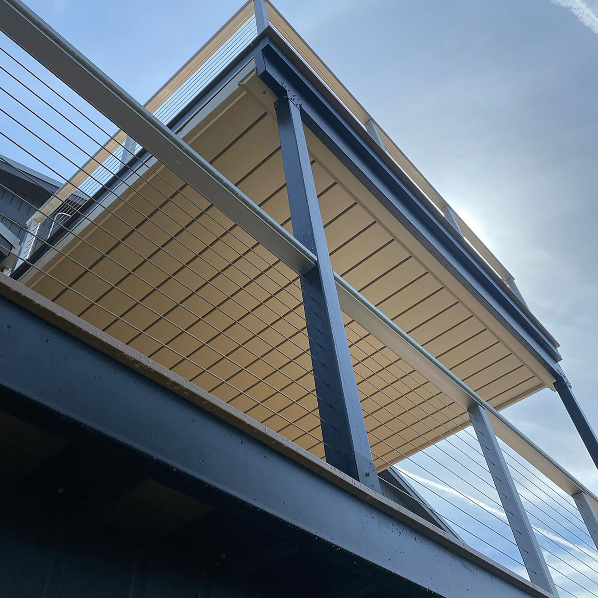 Underneath view of steel deck framing with cable railing on multi-level deck.