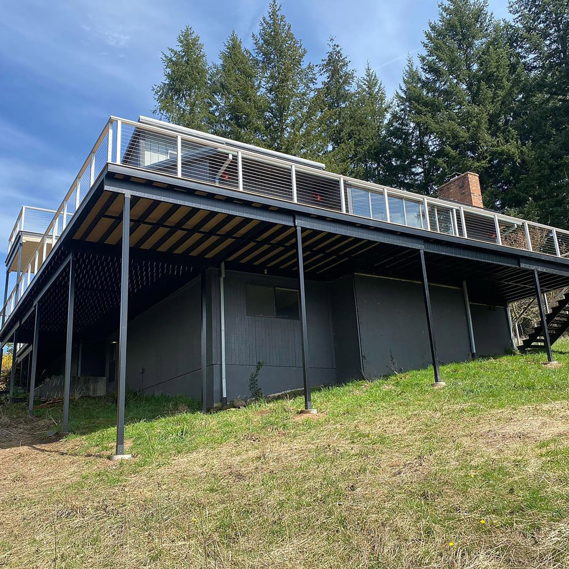 Underneath view of steel deck frame on dark house in background. 