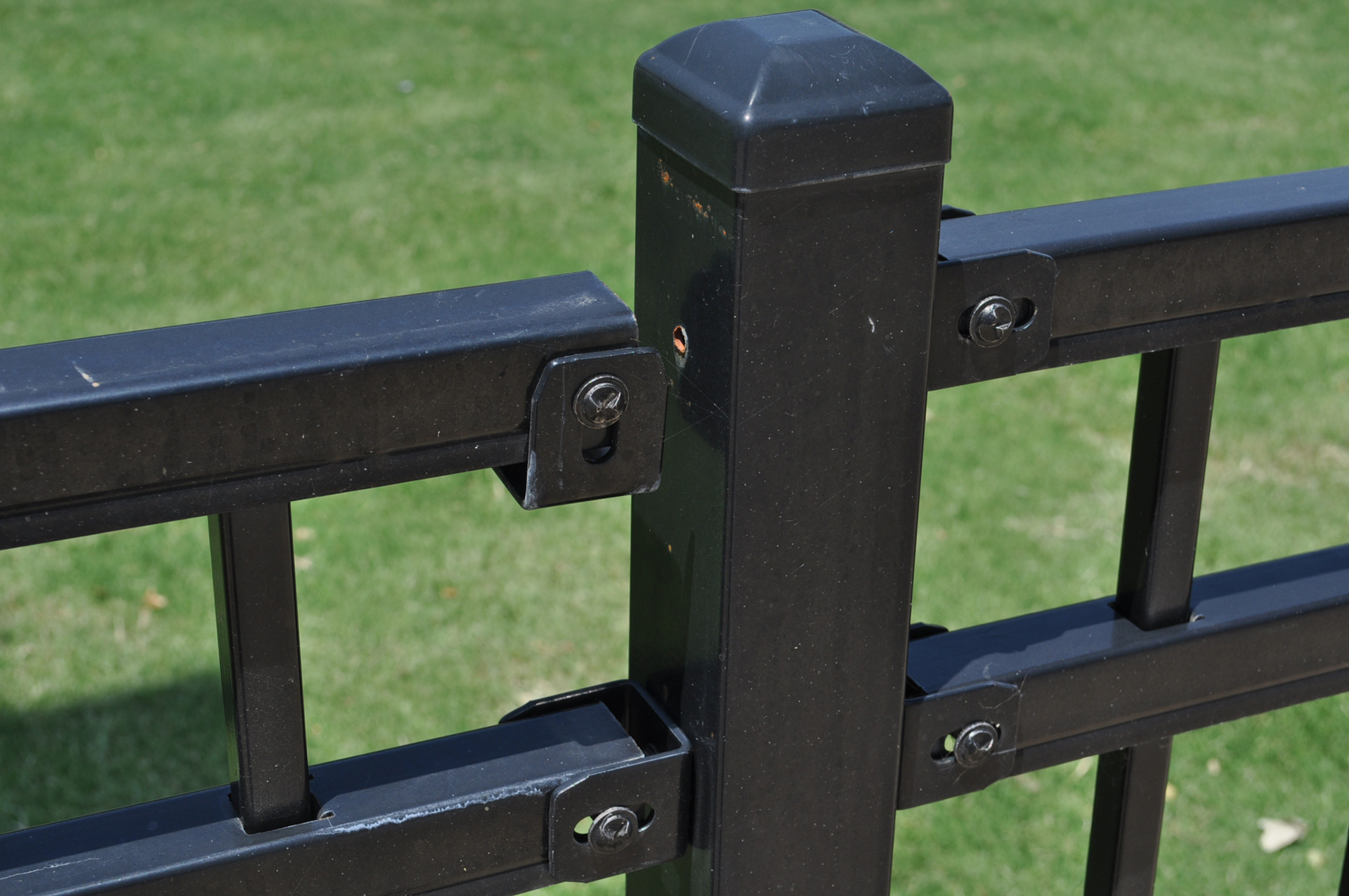 Close up image of a metal fence with a broken exposed fastener. 