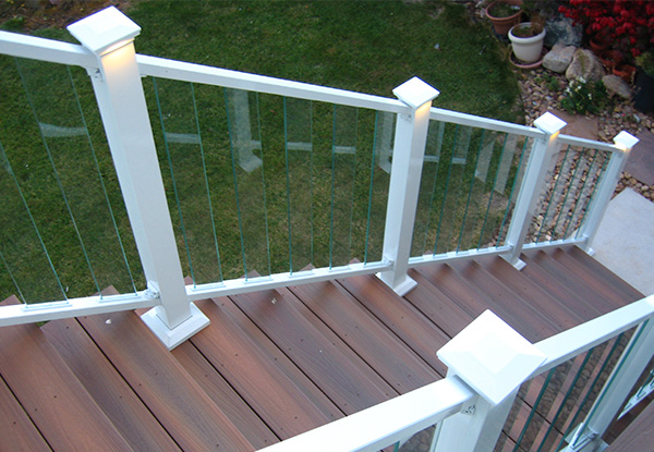 White railing deck with integrated post lights illuminating wooden deck floor.