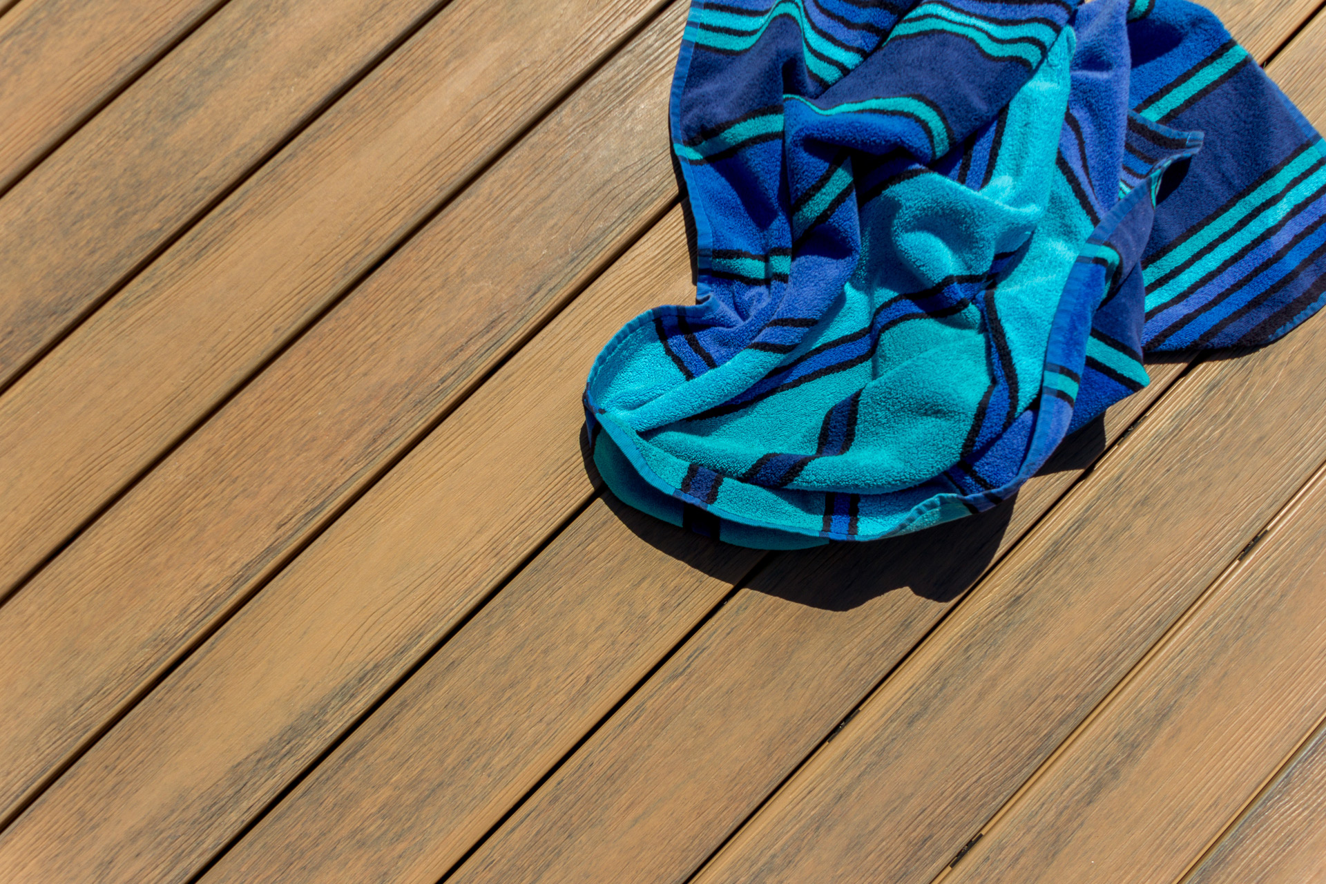 Striped blue towel on a light-colored composite deck.