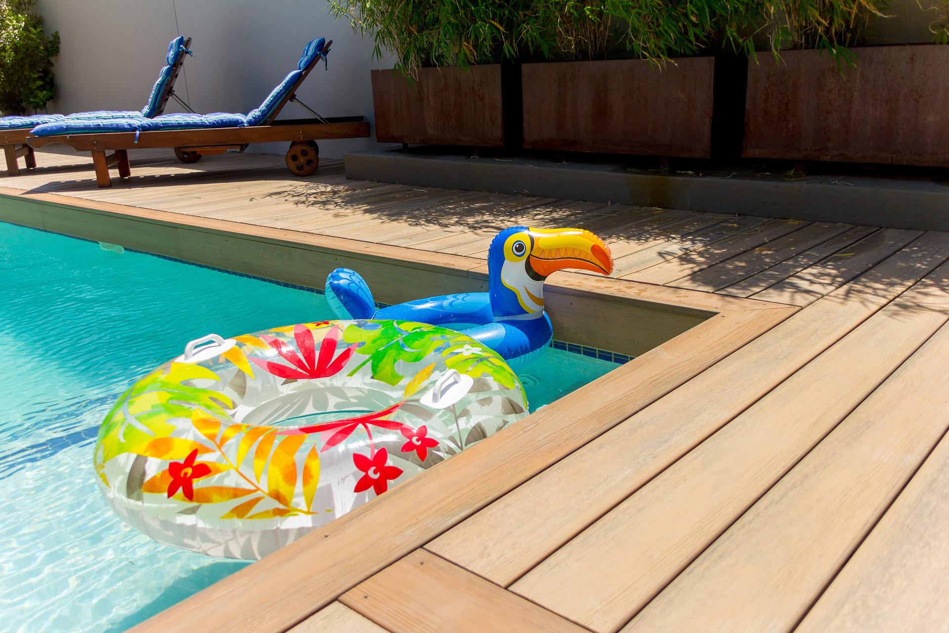 Floating pool toys bump up against light brown composite decking.