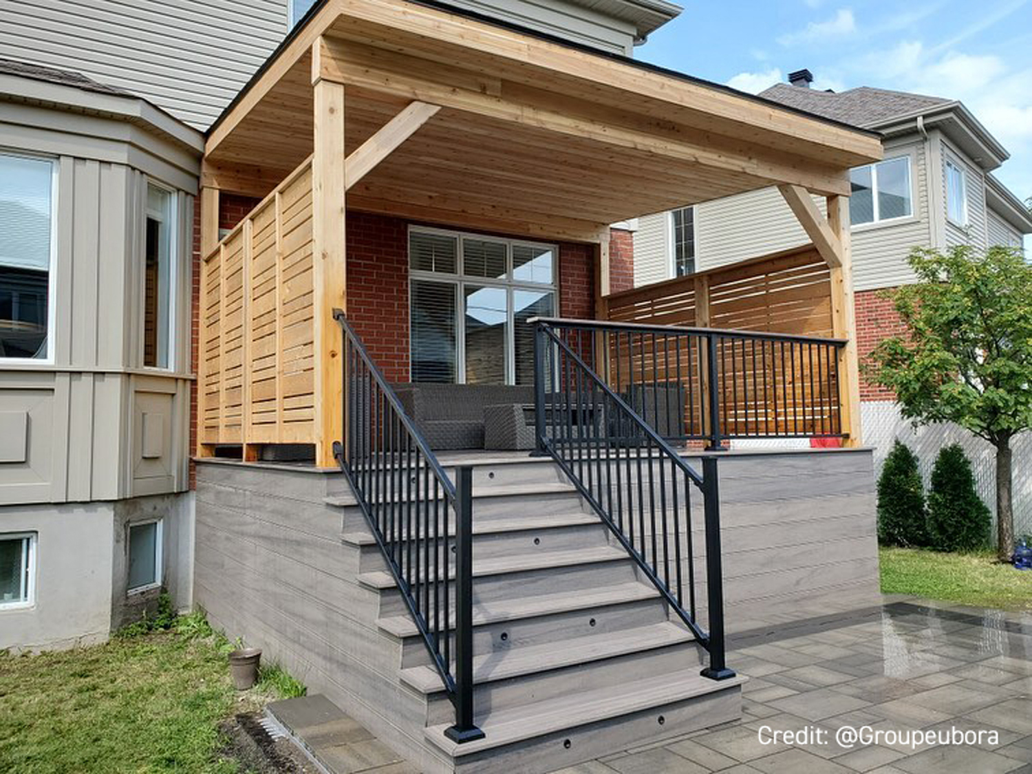 Back patio of a tan house with steps with metal railing leading to the backyard.