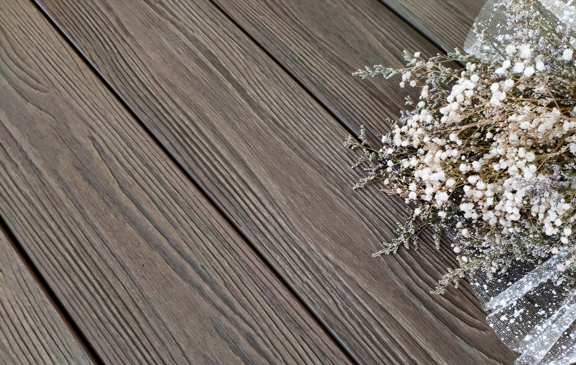 Close up of dark bamboo composite decking with white flower bouquet off to the side.