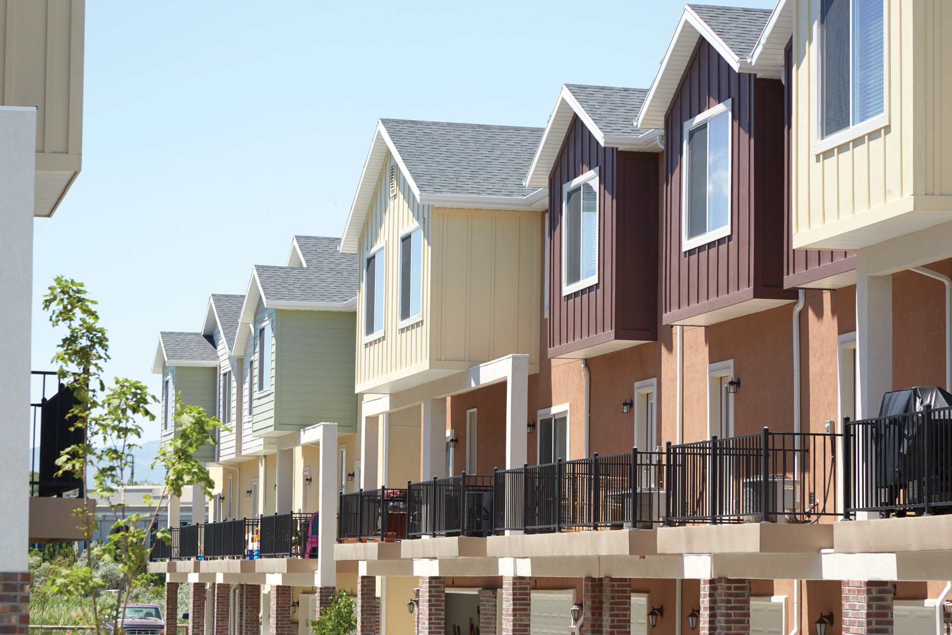 Colorful multi-family homes with steel railing patios on the back. 