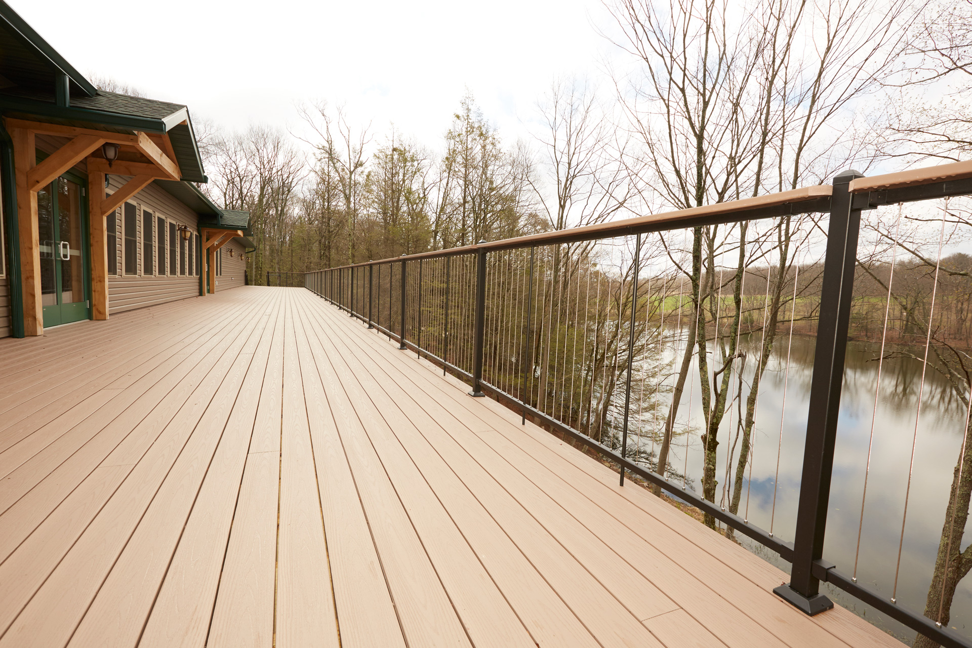 Outdoor deck of commercial building with vertical cable railing with serene pond in the background. 