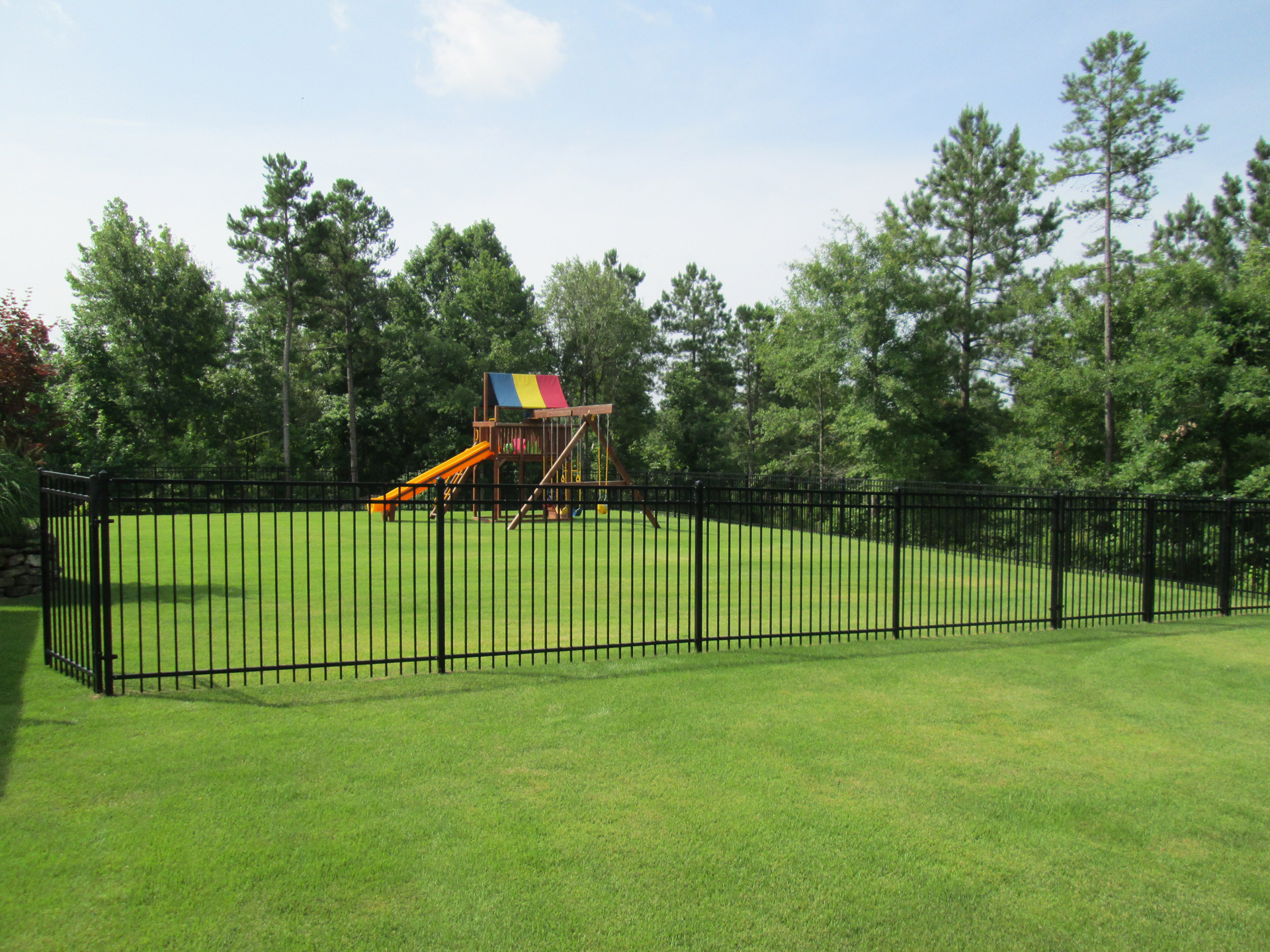Steel fence panels enclosing a large playground acre. 