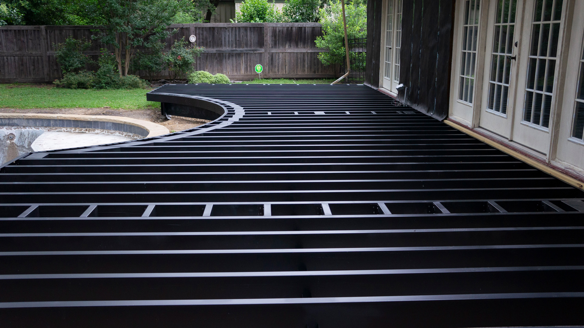 Curved deck framing waiting for decking materials in the backyard of a home.