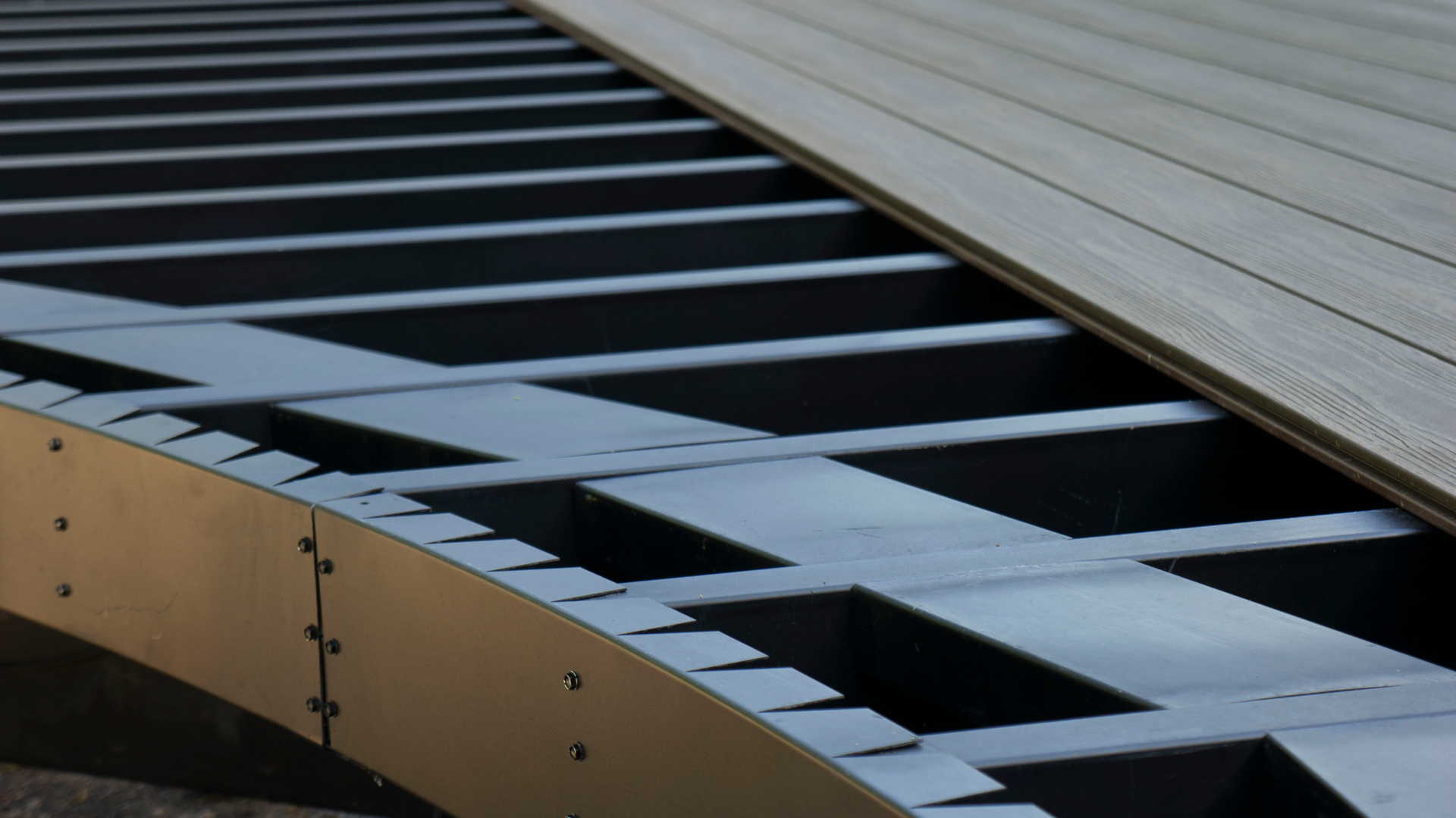 Close up view of steel framing underneath a half-finished curved deck.