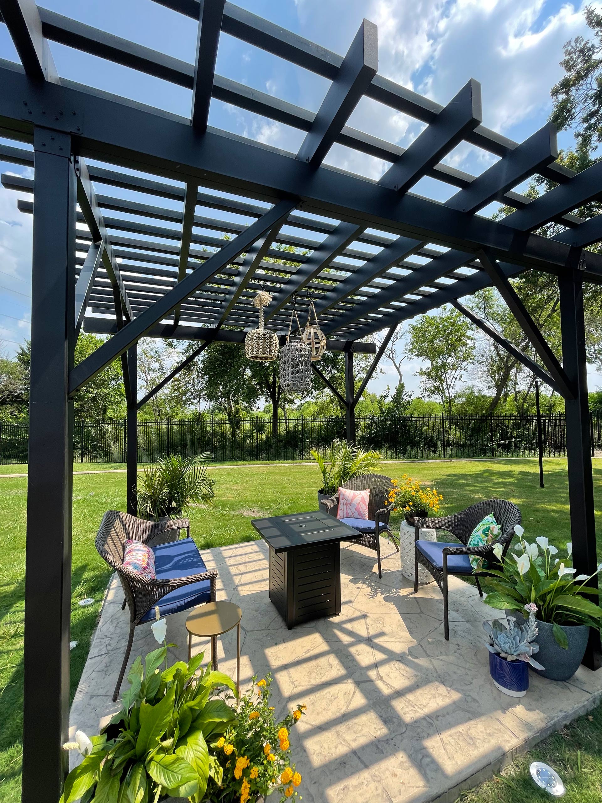 Backyard living space created with an overhead steel pergola complete with chairs and plants.