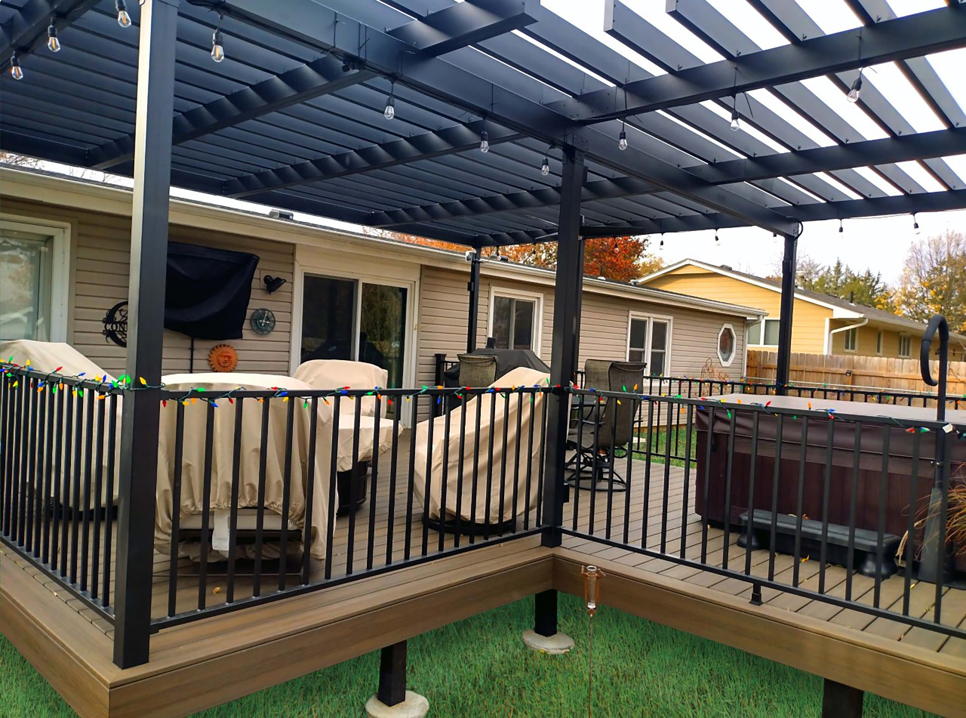 Backyard view of a home featuring a steel pergola over a deck.
