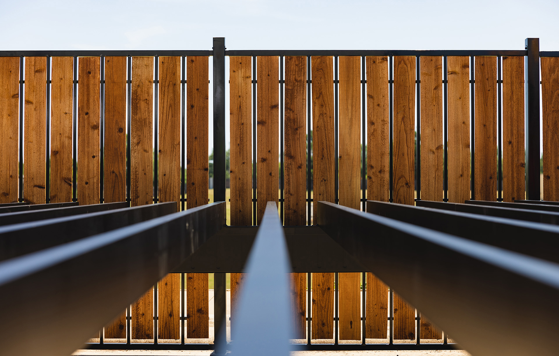 Sideview of steel deck frame shown beside wooden fence. 