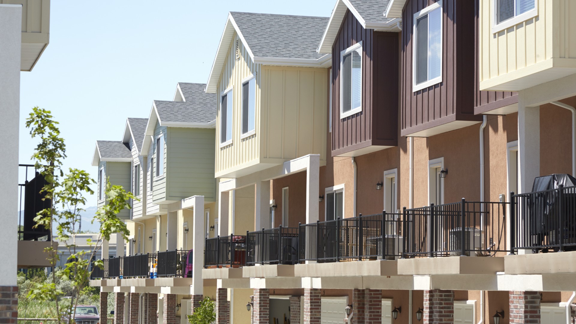 Row of townhouses with modern balcony railings in various colors.