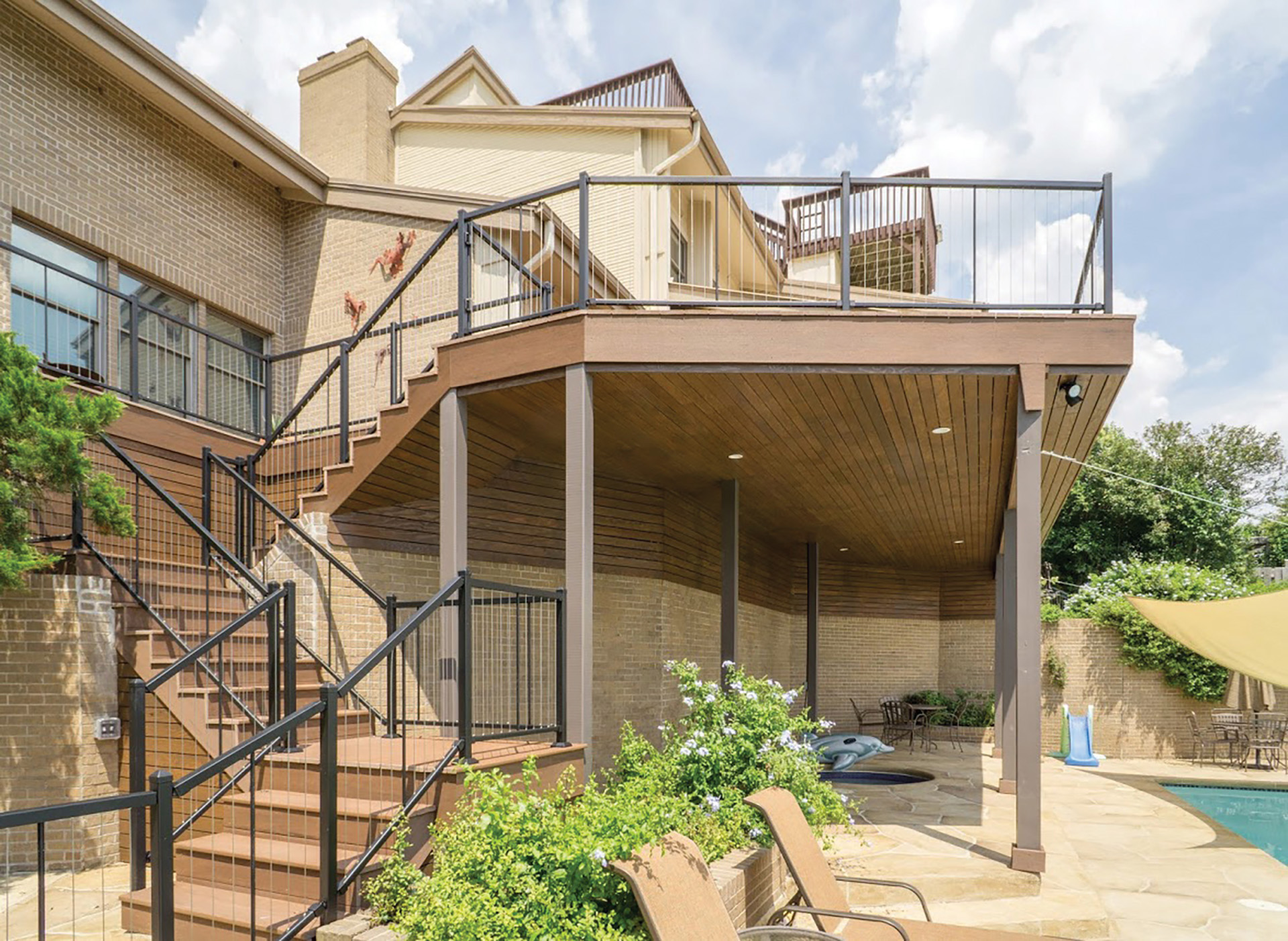 Multi-level outdoor deck featuring steel deck railings, overlooking a pool and patio area