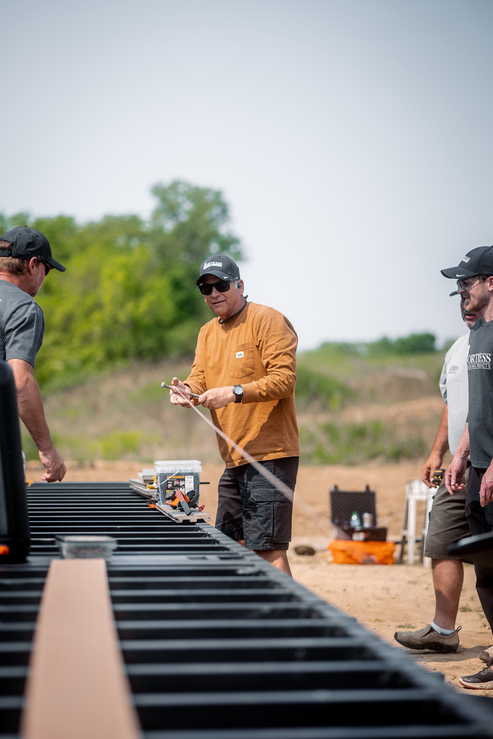 Multiple men building a steel deck frame with tools laying around on the ground.