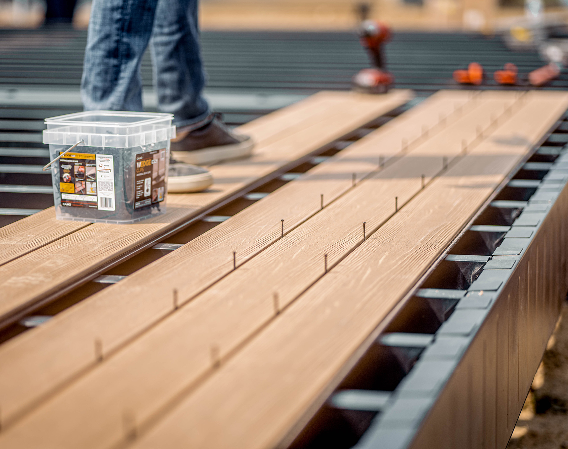 Person standing on composite deck boards during installation on a steel frame.