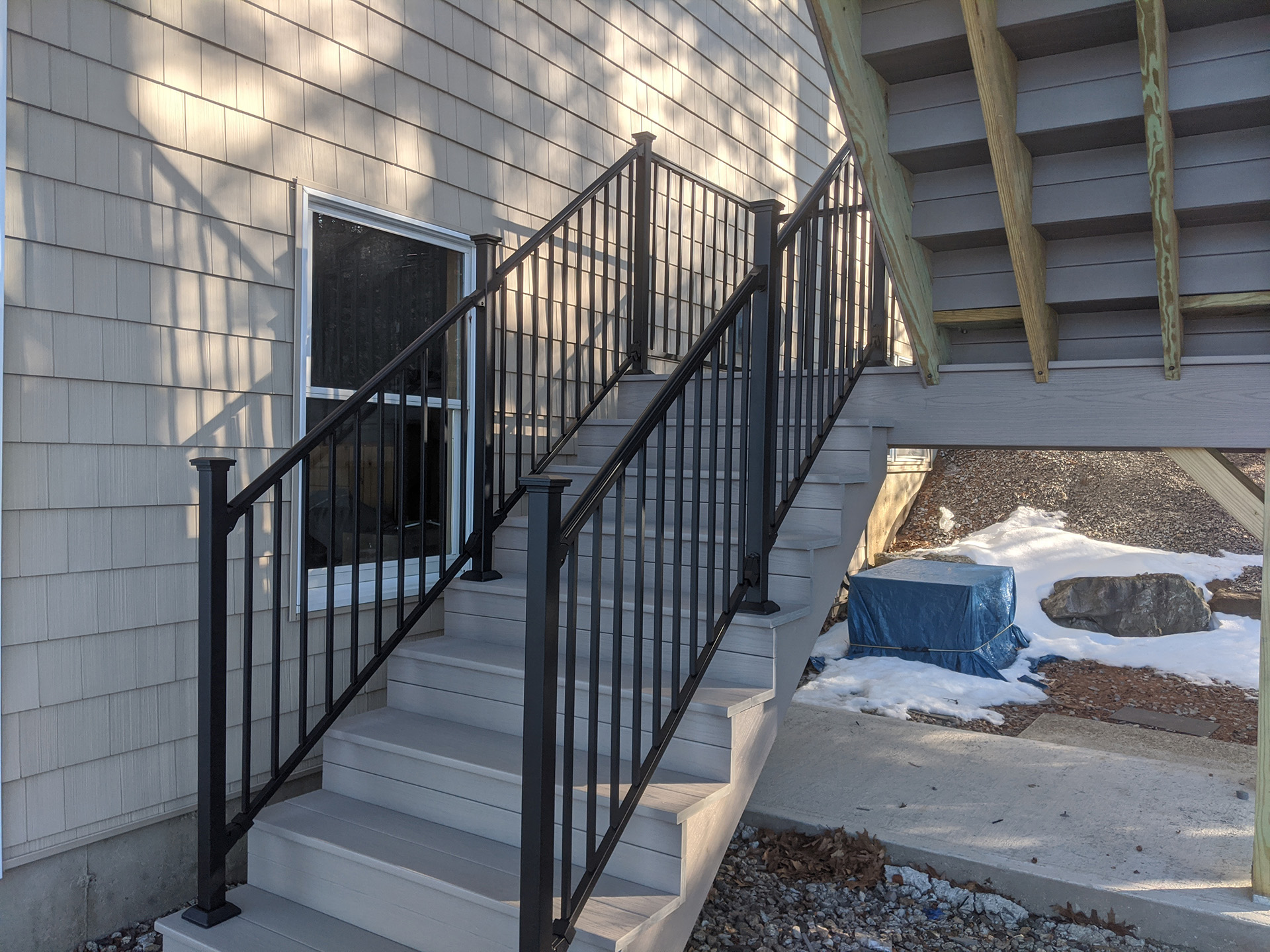 Metal railings on deck stairs with house in the background.