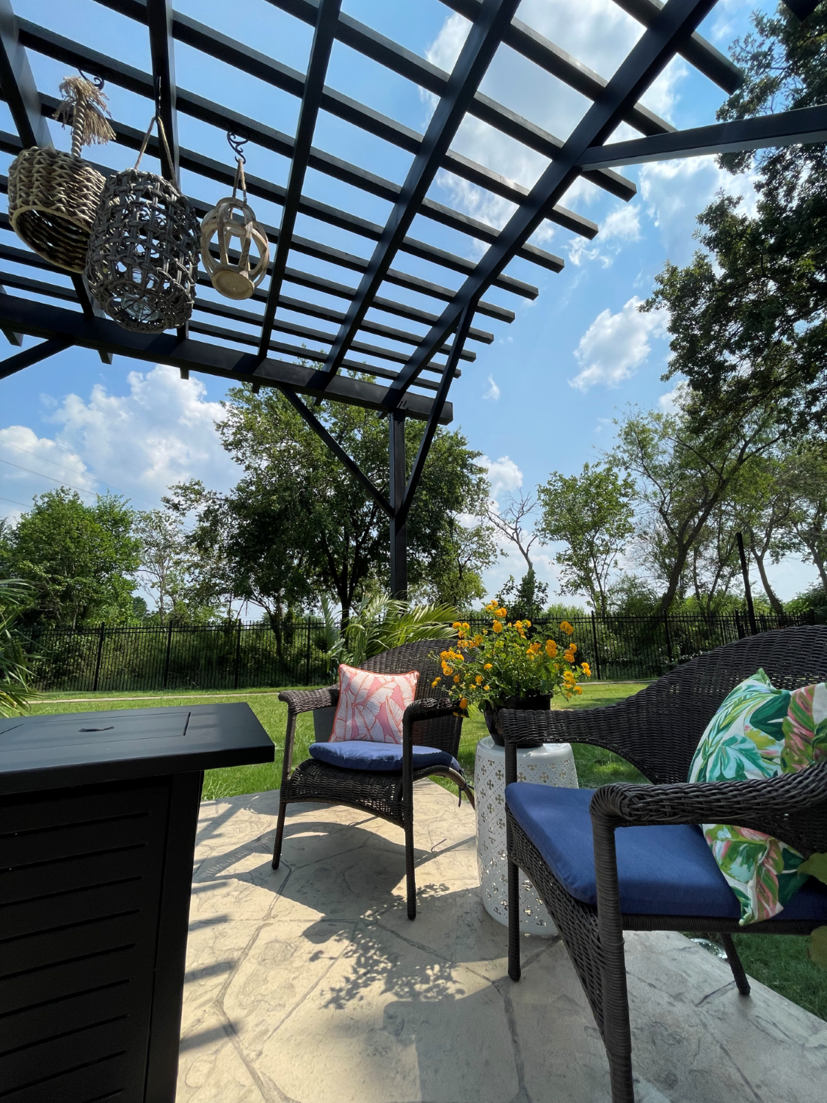 Close up view of an outdoor pergola over a sitting area with trees in the background. 