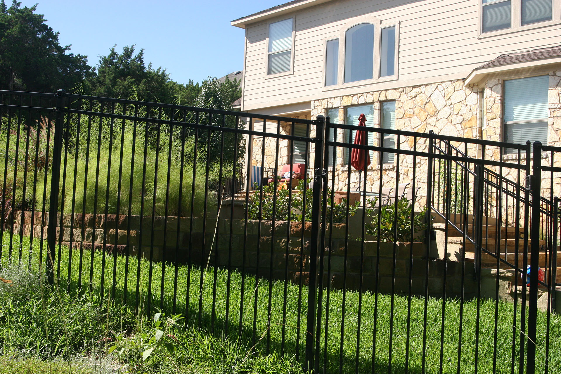 A black steel fence surrounds a house, highlighting its residential setting and providing security and privacy.