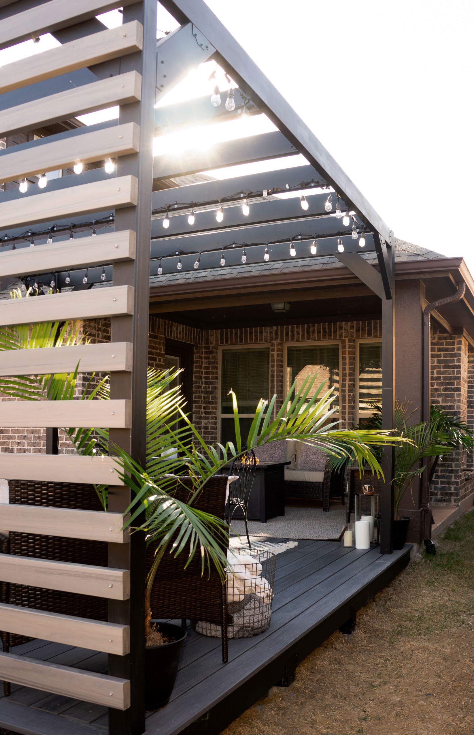 Modern steel pergola extending the outdoor living space with couches and greenery.