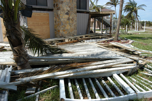 Collapsed wood deck structure damaged by severe weather near coastal home.