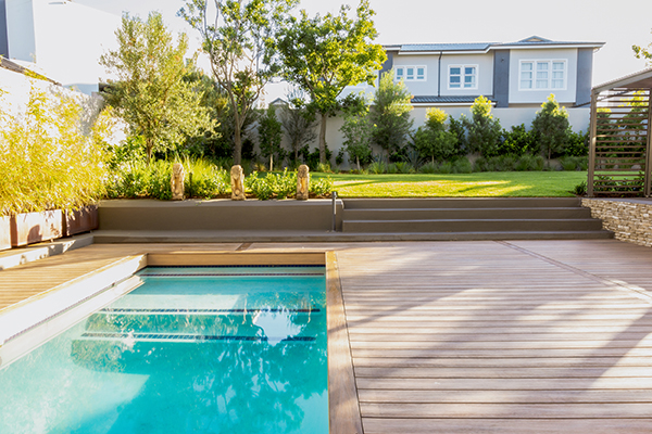 Small pool area with a composite deck surrounding it with stairs to lawn in background.