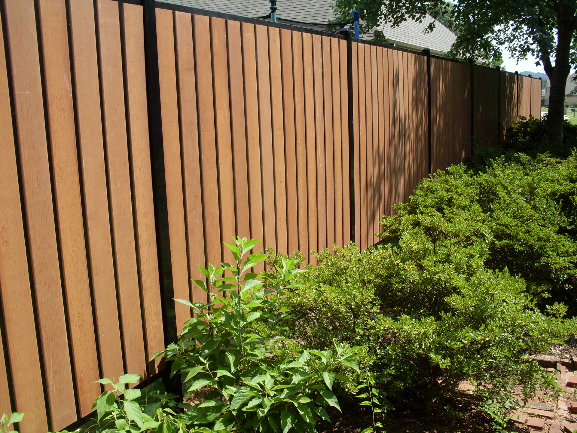steel privacy fence with composite picket boards along bushes