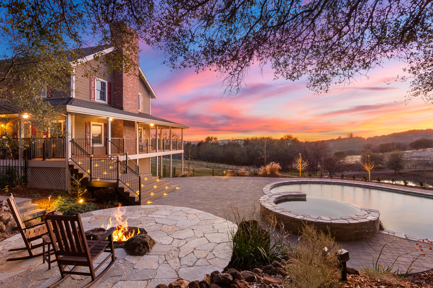 Patio behind home with a colorful sunset over a serene fireplace.