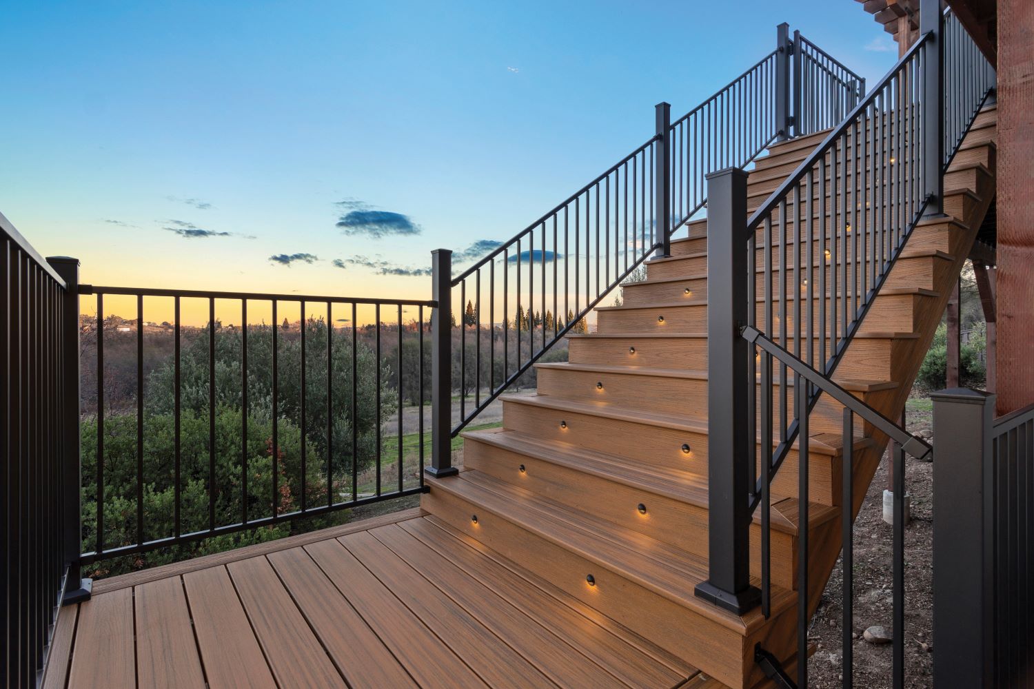 Escaleras de decks de acero con baranda Fortress e iluminación al atardecer en vista panorámica.