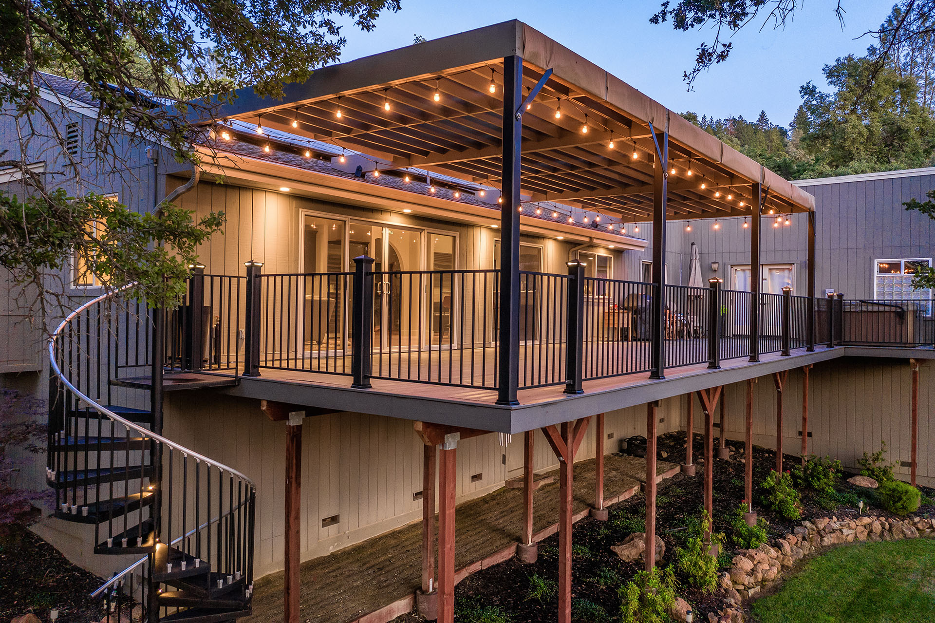 Outdoor patio with hanging string lights overhead with metal railings on the stairs leading to the floor below.