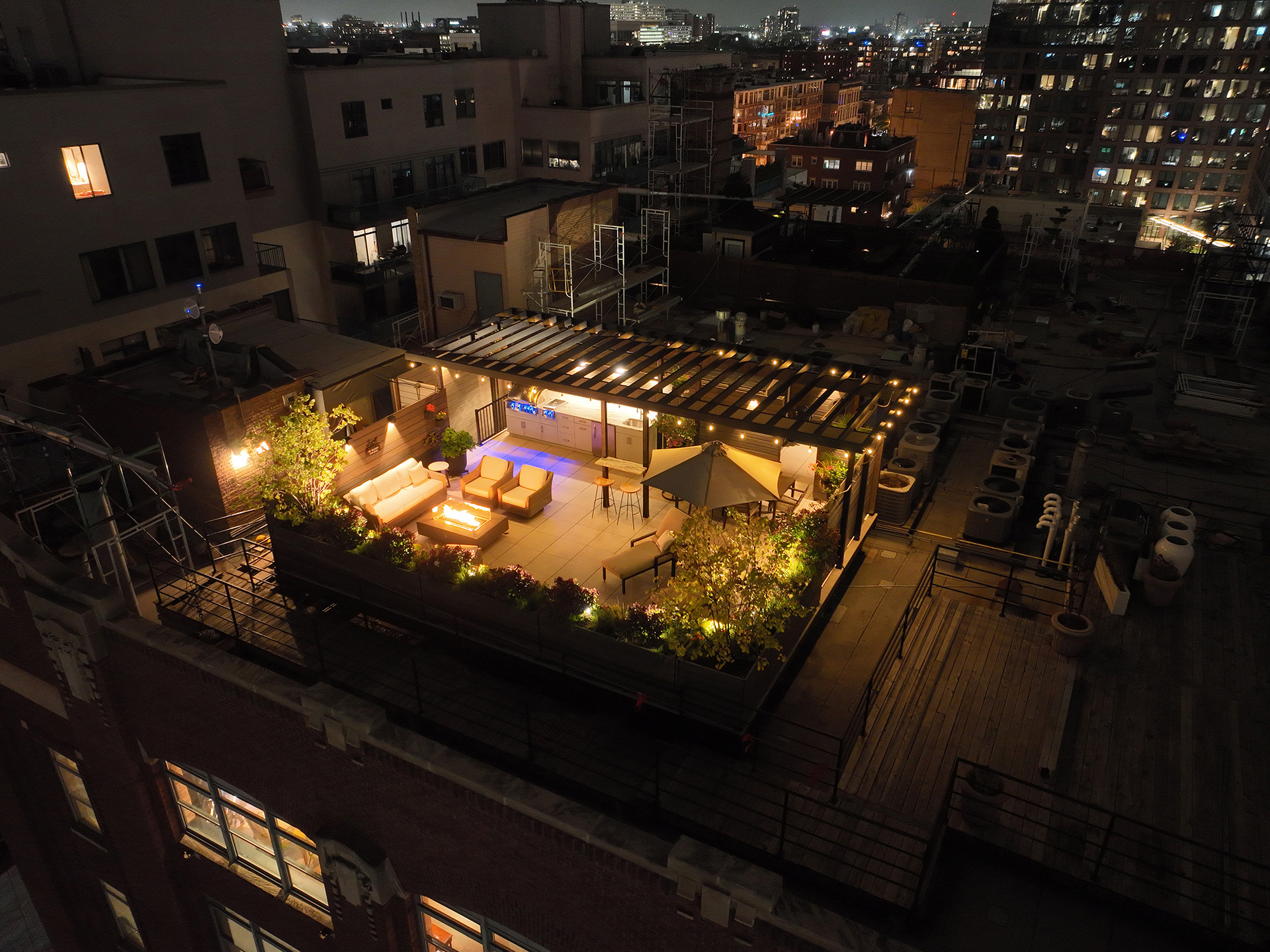 Nighttime view of a rooftop terrace featuring a modern steel pergola with integrated lighting.