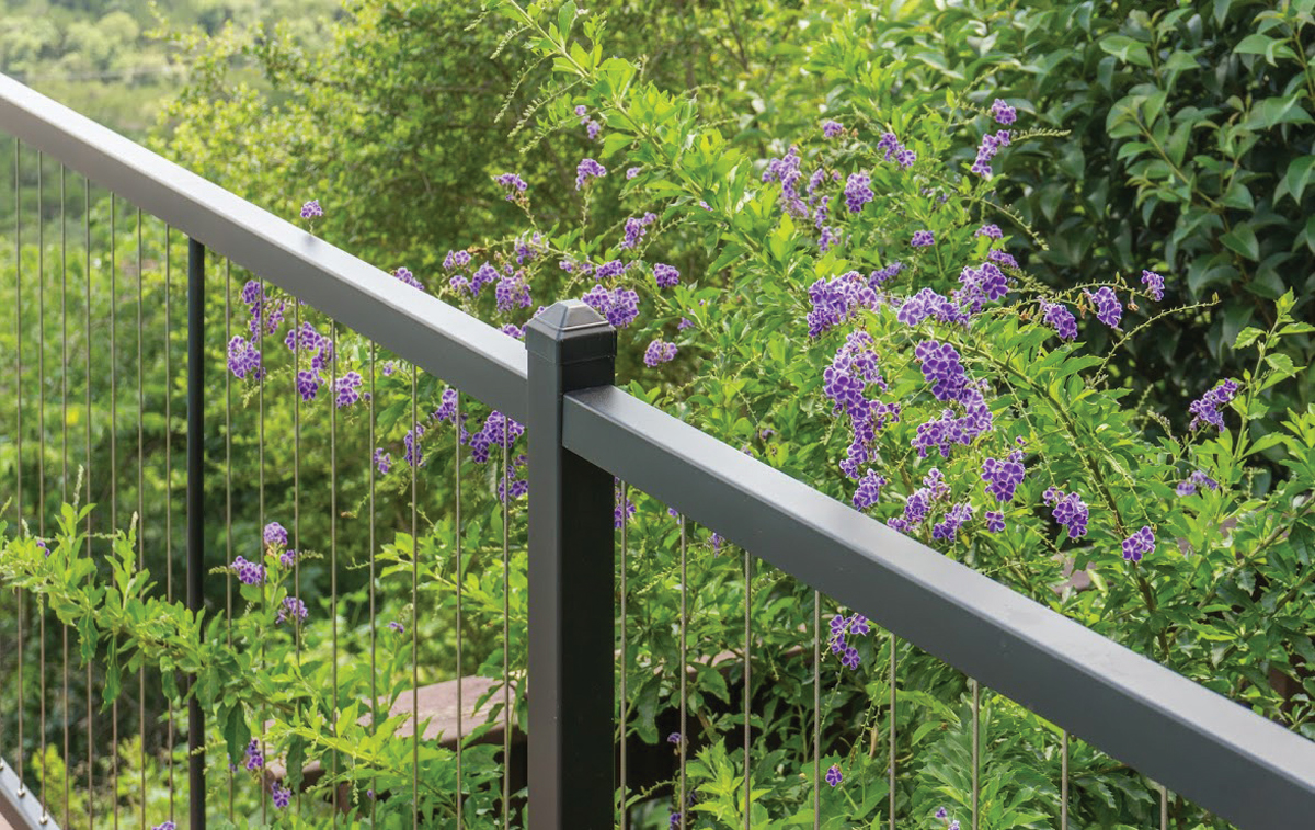 Cable railing with purple flowers in the background.